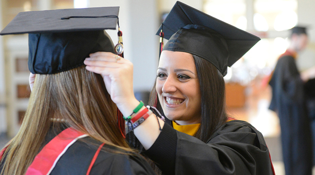 Two graduates adjusting their caps before the commencement ceremony.